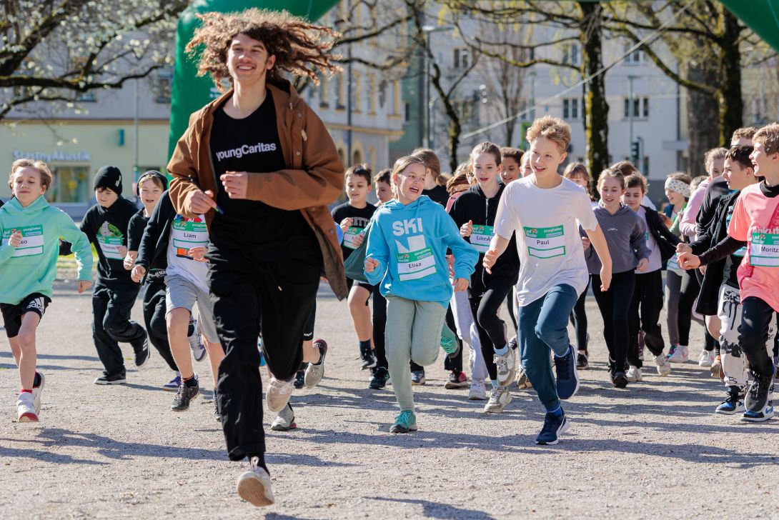 Eine Gruppe von Kindern und Jugendlichen läuft mit Begeisterung bei einer Schulveranstaltung im Freien.