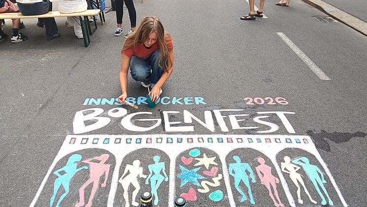 Frau malt mit Straßenkreide bei Bogenfest auf die Straße