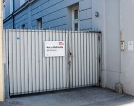 Ein metallisches Tor mit dem Schild 'Notzufahrt' in einer städtischen Umgebung.