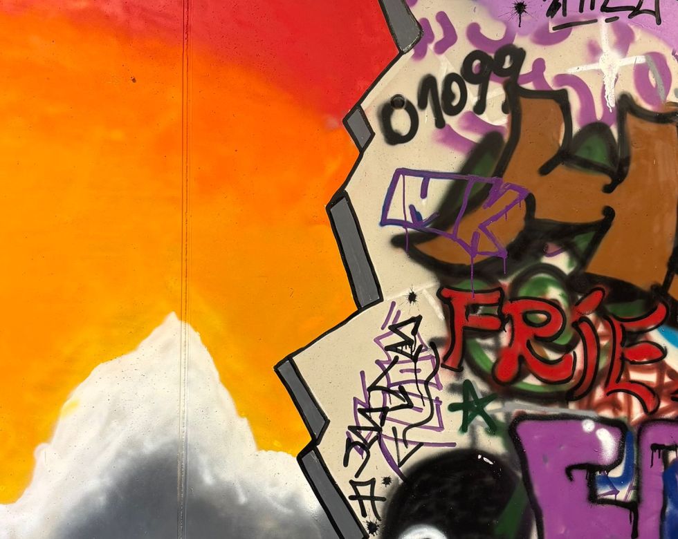 Ein farbenfrohes Graffiti, das einen Sonnenuntergang und verschiedene künstlerische Elemente darstellt.