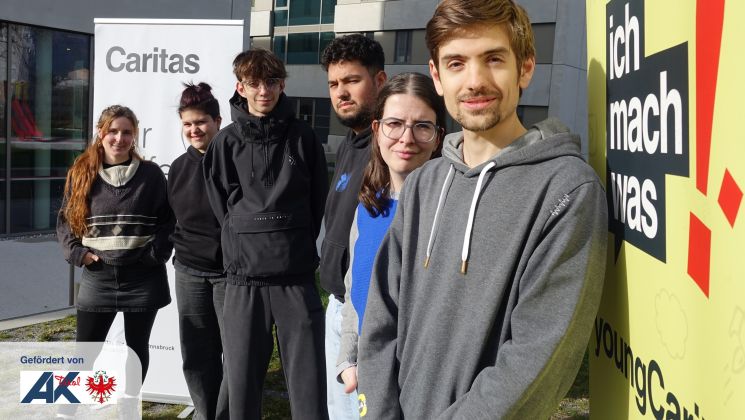 Fünf junge Menschen stehen vor einem Gebäude neben einem „ich mach was“-Schild.