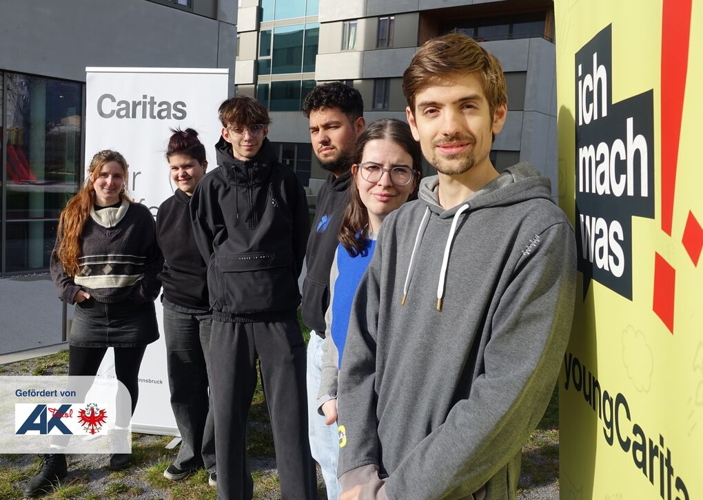 Fünf junge Menschen stehen vor einem Gebäude neben einem „ich mach was“-Schild.